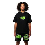 A person with curly hair rocks a galactic streetwear look, wearing the BEAT THE ODDS S/S TEE BLACK and shorts with neon green and white graphics plus a bold B logo, all set against a plain white background.