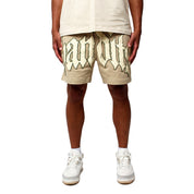 A person stands against a white background wearing EGO SWEATSHORT TAN with bold black 3D Puff Print Gothic lettering, beige T-shirt, and white sneakers. The image is cropped at the torso to highlight the shorts and lower body.