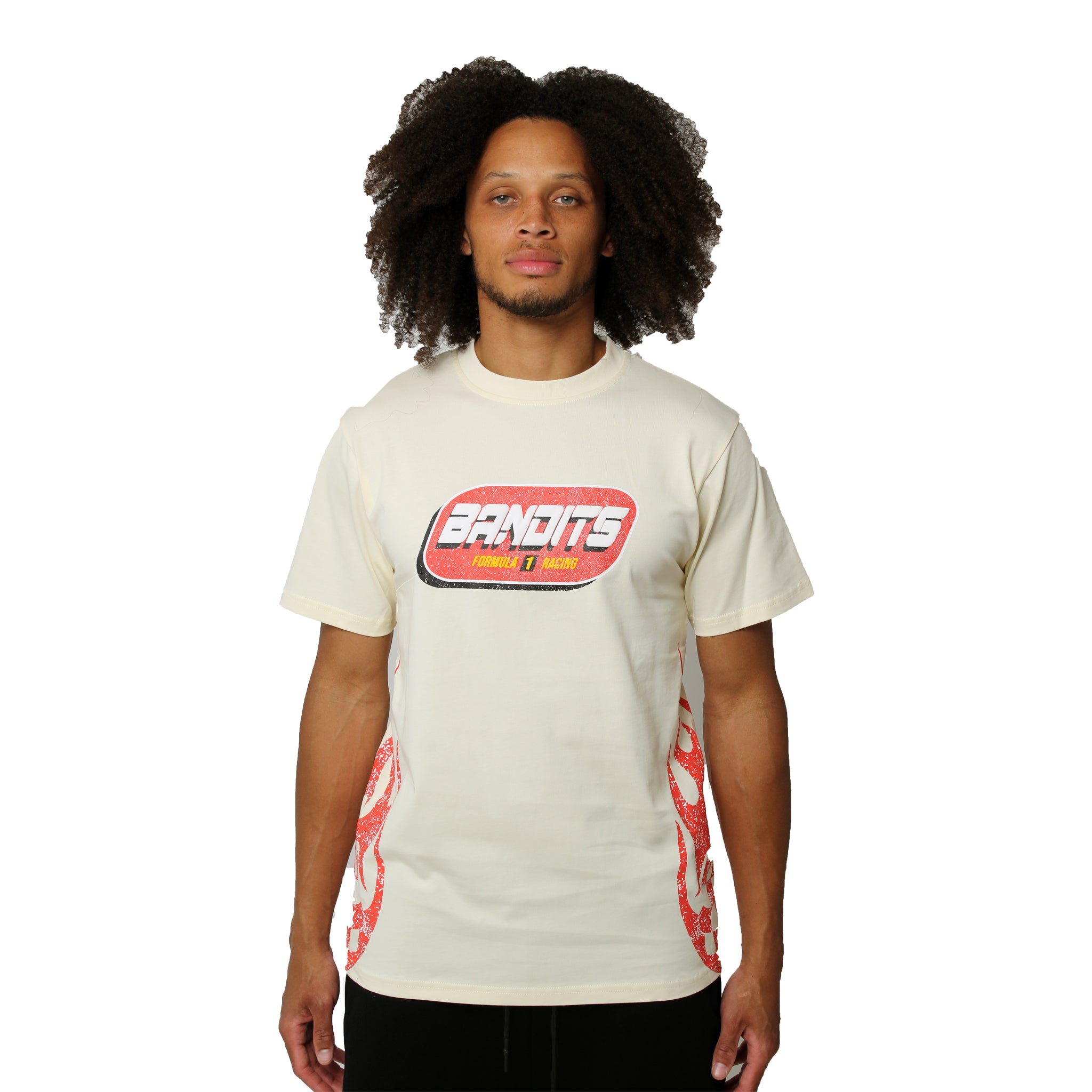 A man with curly hair wears the FORMULA ONE S/S TEE CREME, a cream racing t-shirt with bold BANDITS lettering and red patterned side panels, channeling vintage race vibes against a plain white background.