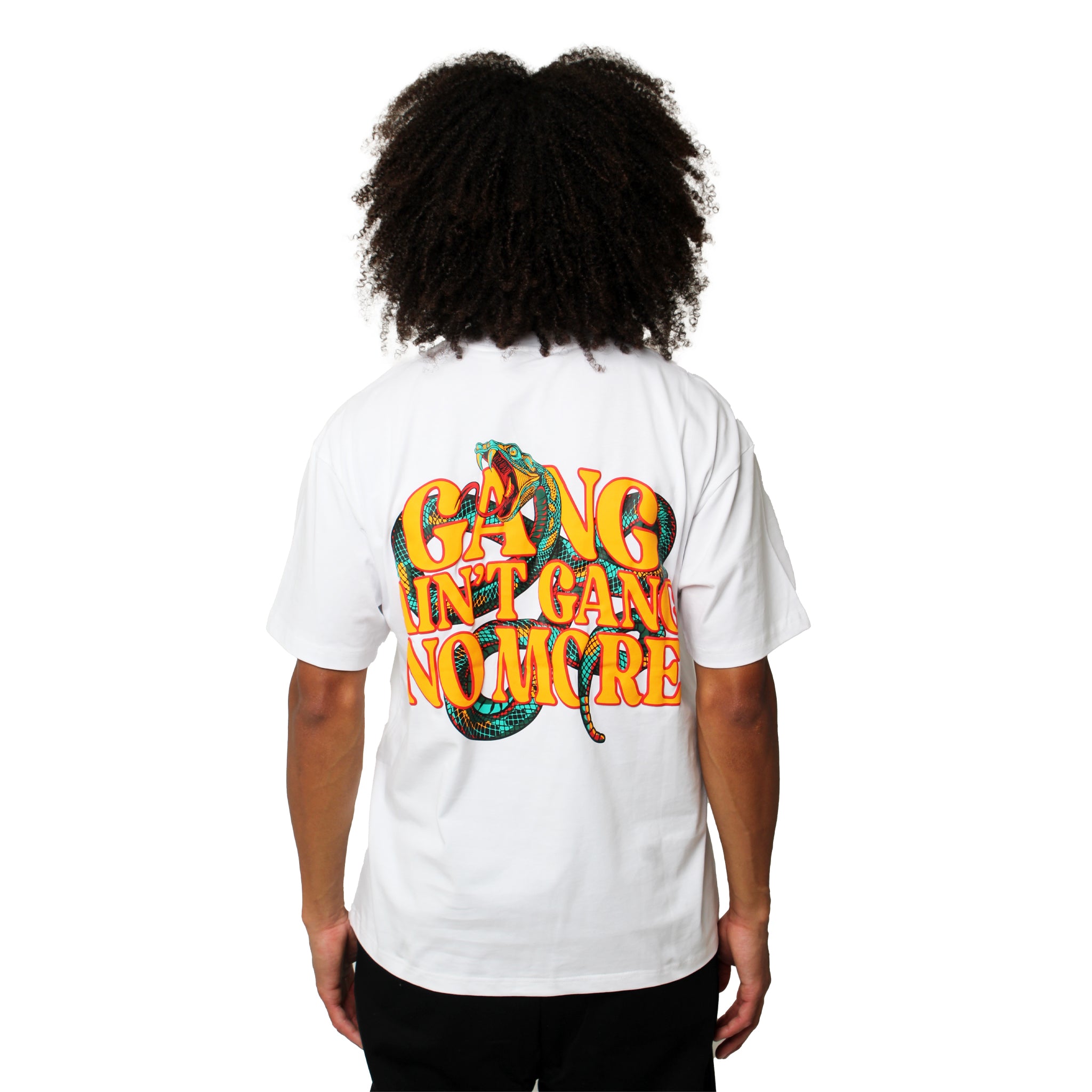 Person with curly hair wears the GANG AIN'T GANG NO MORE S/S TEE WHITE—an oversized, heavy cotton shirt with colorful puff printed text and a snake graphic on the back. Plain white background.