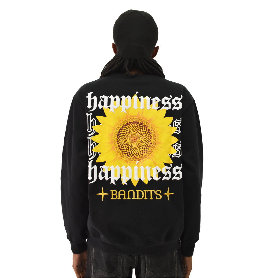A person wears the HAPPY DAYS CREWNECK SWEATSHIRT BLACK, featuring a vibrant sunflower graphic with "happiness" and "BANDITS" in bold, decorative fonts around the flower.