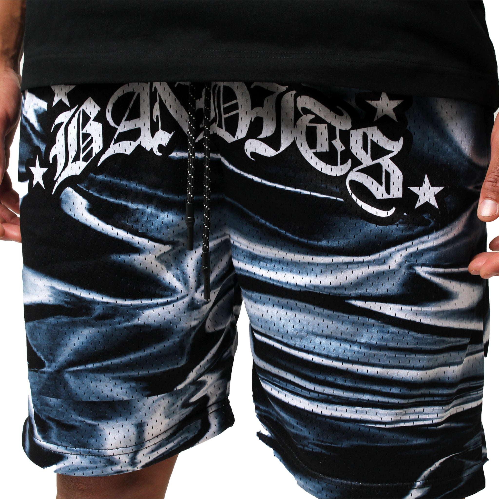 A person is wearing IRIDESCENT MESH SHORTS BLACK, featuring a black and white pattern and double-layered mesh, with "BANDITS" and stars printed in stylized white letters across the true-to-size waistband. Their hands are at their sides.
