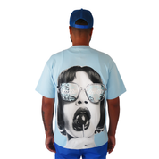 A person wearing a blue cap, blue shorts, and the LOLLIPOP S/S TEE BLUE from Bandits—featuring a retro portrait of a woman in sunglasses eating a lollipop—stands with their back to the camera against a white background.