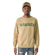 A man in the ONLY THE STRONG SURVIVE CREWNECK SWEATSHIRT TAN with a 3D Puff Print "BANDITS" graphic and matching cap stands facing forward in ripped blue jeans. The heavyweight French terry fleece blends comfort and style against a white background.