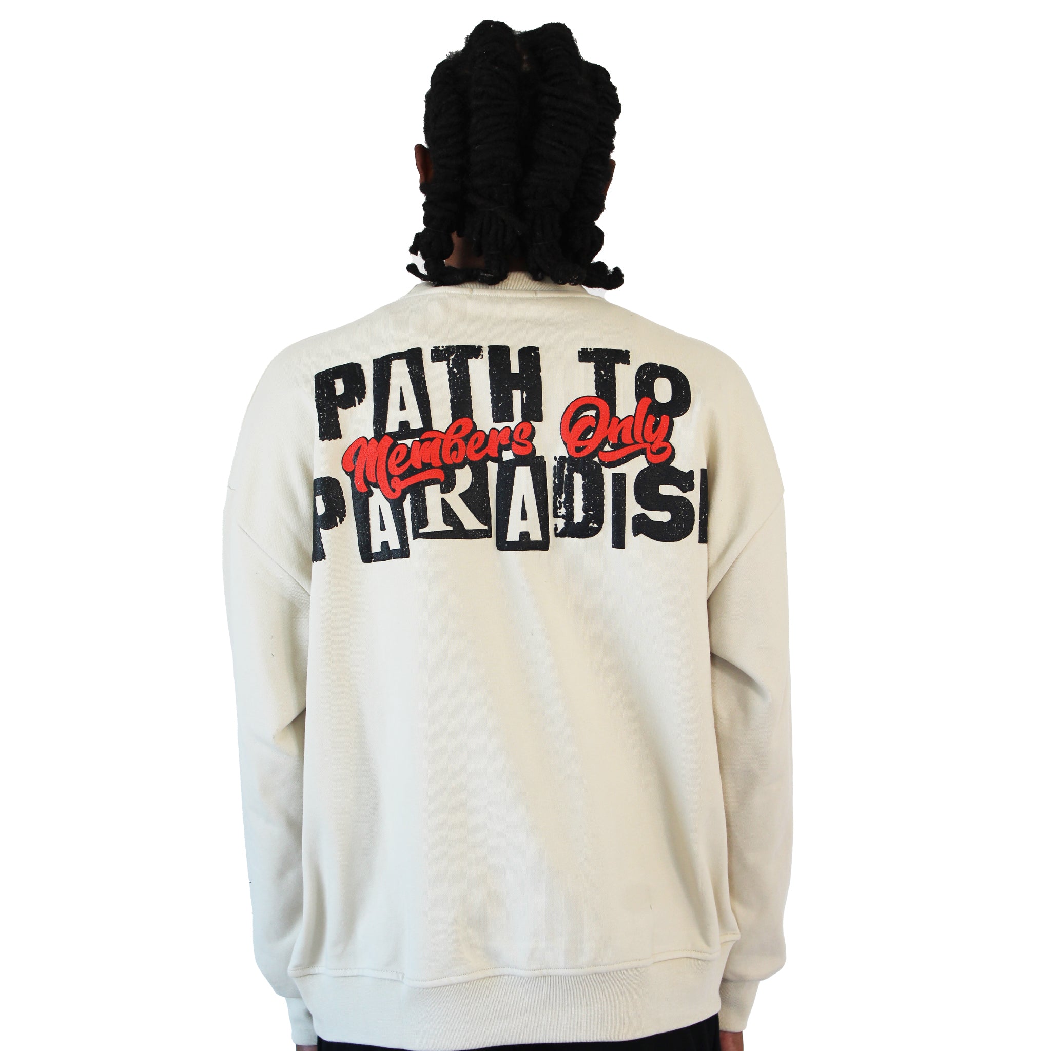 A person with dark, shoulder-length hair wears the PATH TO PARADISE CREWNECK SWEATSHIRT in tan. The oversized crewneck features bold “PATH TO PARADISE” text on the back, with “Members Only” in red script—a standout streetwear piece.