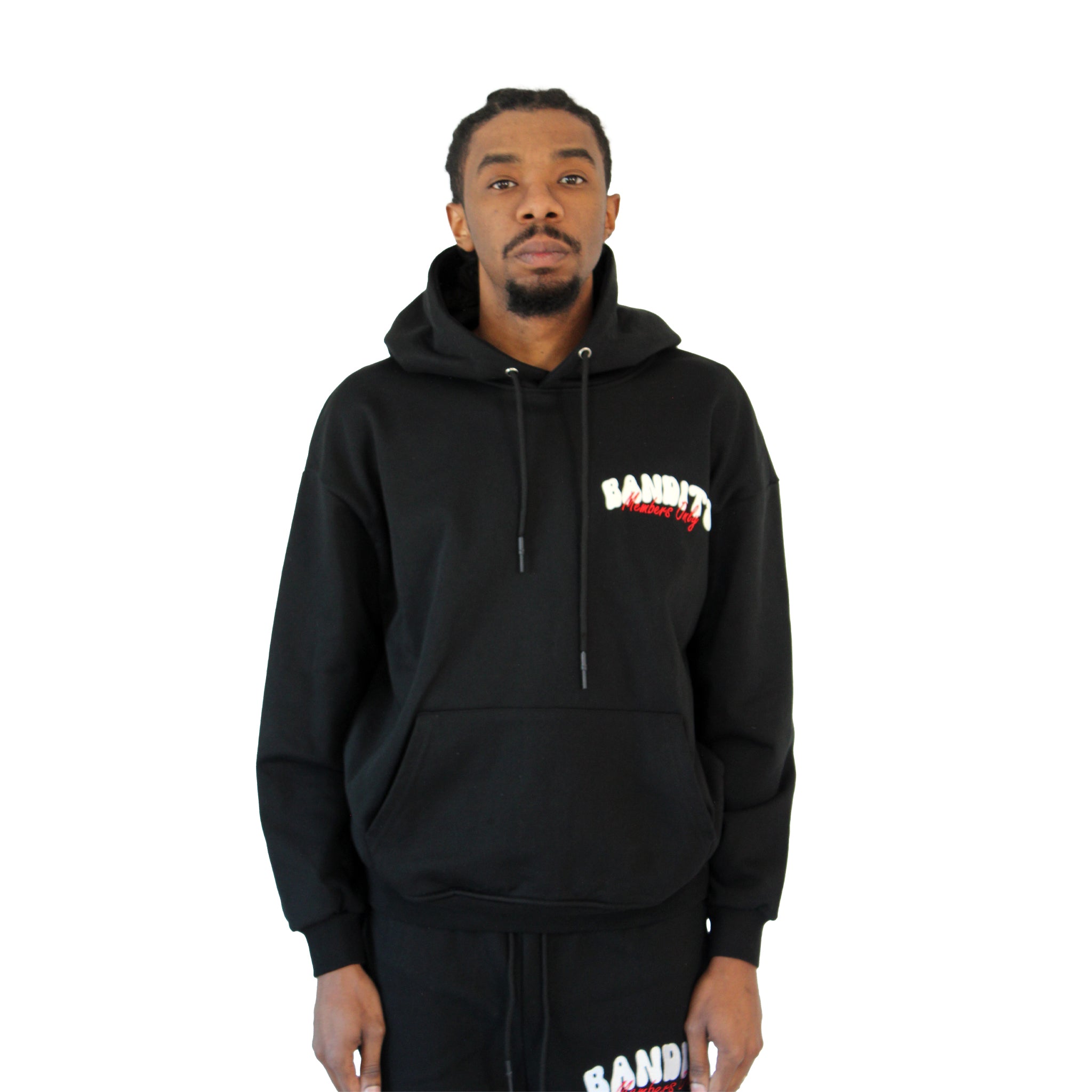 A man stands against a white background wearing the BIKER CLUB PULLOVER HOODY BLACK and matching black pants, both featuring bold white and red BANDIT lettering on the chest and thigh.
