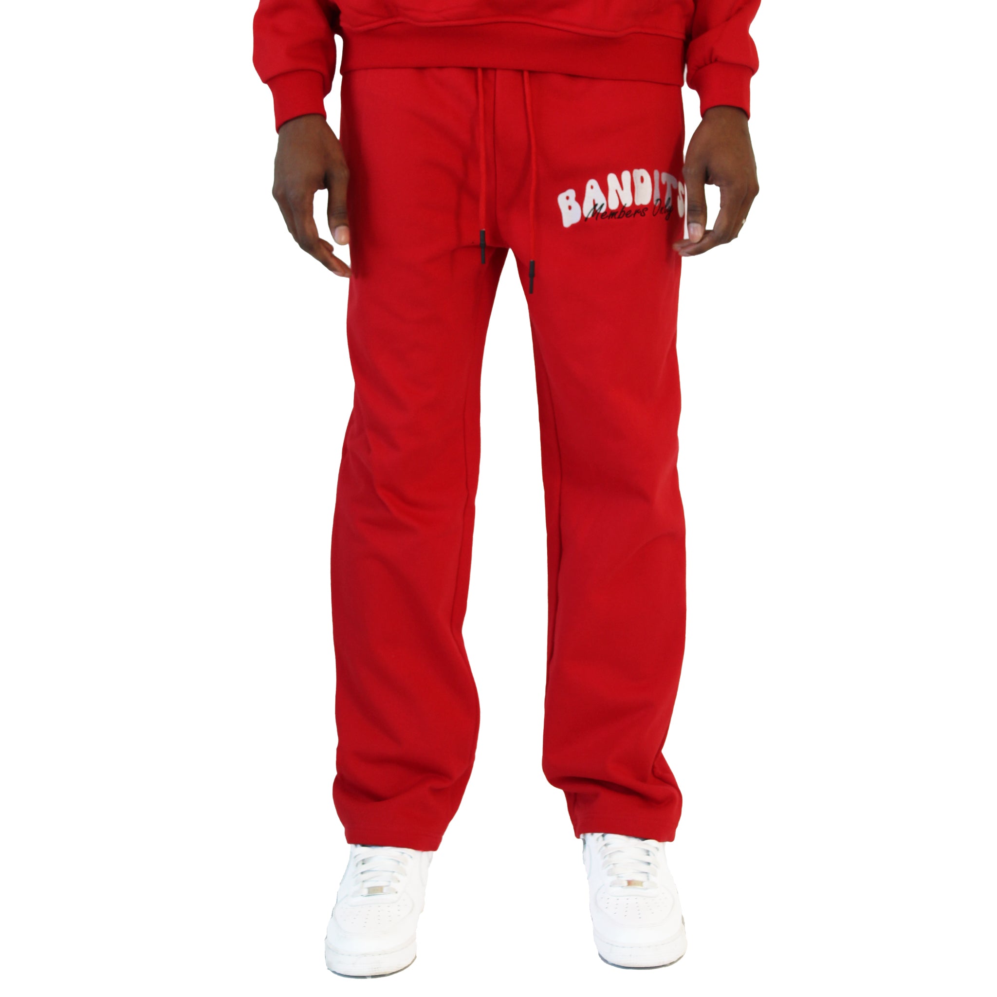 A person wearing BIKER CLUB SWEATPANTS RED with "BANDIT" in white on the left thigh, styled with white sneakers. The image shows the trendy streetwear sweatpants from the waist down.