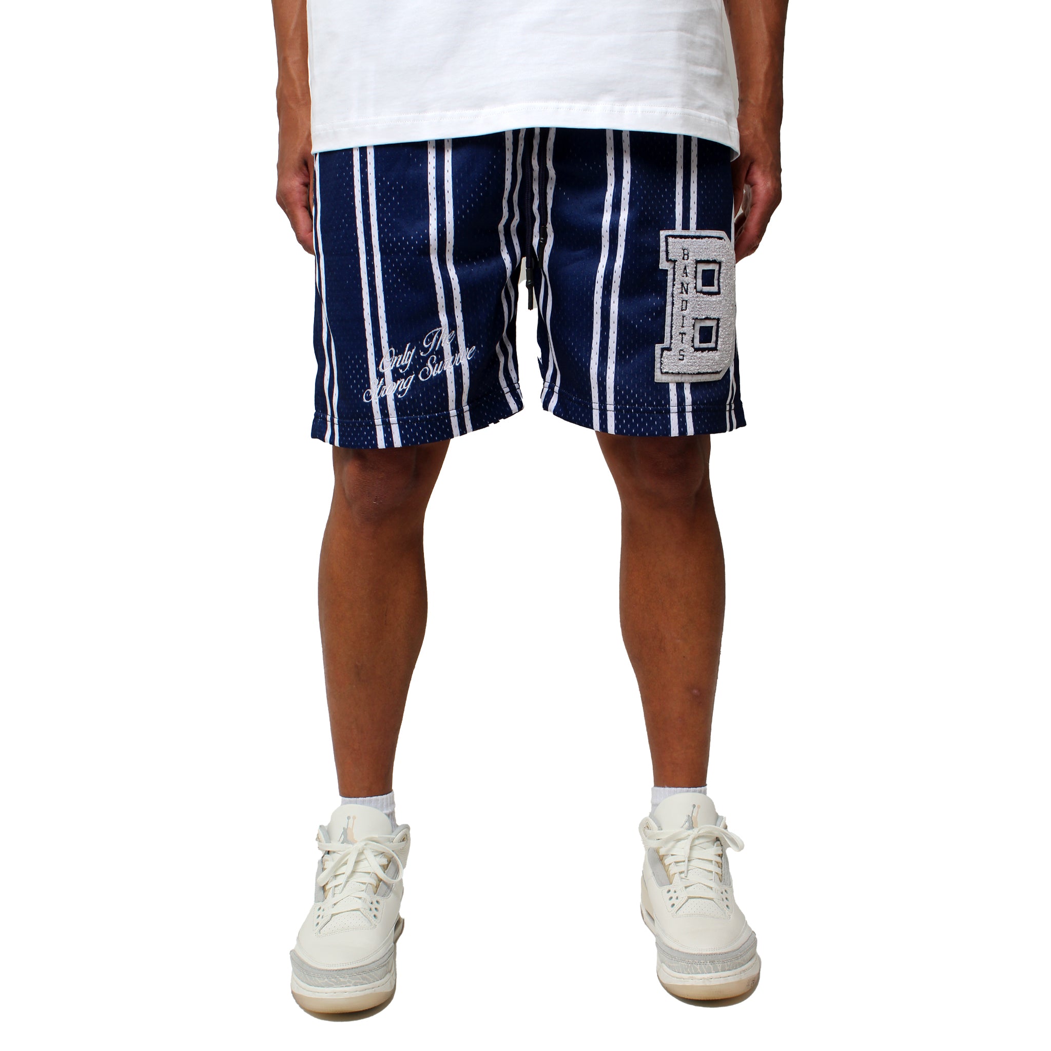 A person in true to size ONLY THE STRONG SURVIVE MESH SHORTS NAVY—navy blue, double-layered mesh with chenille embroidery and a large B patch—paired with a white t-shirt and sneakers, stands against a white background.