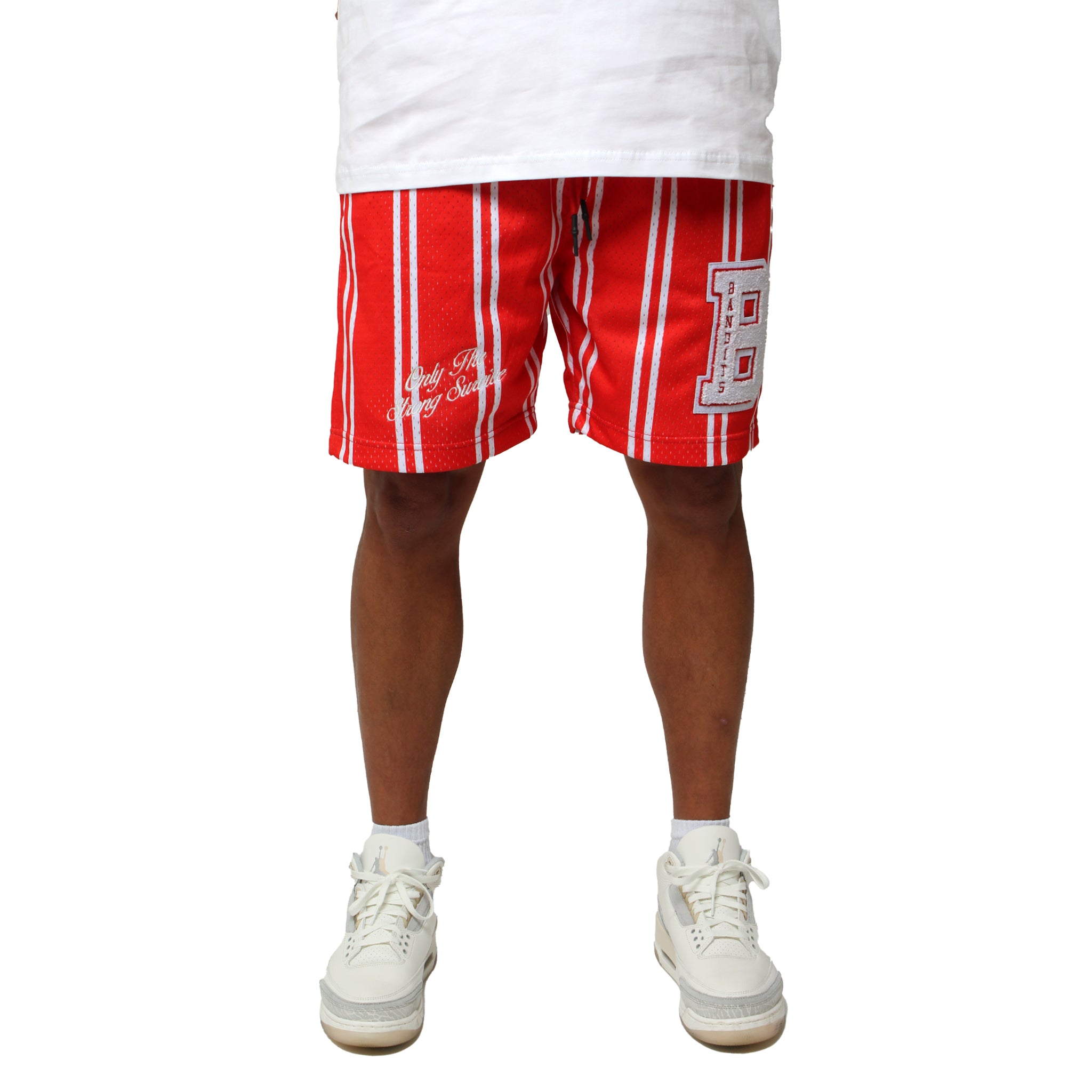 A person wears ONLY THE STRONG SURVIVE MESH SHORTS RED with a large chenille letter B patch and white sneakers, standing against a white background. Only their legs and the lower part of a white shirt are visible. Shorts fit true to size.