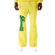 Wearing the VARSITY SCRIPT SWEATPANTS LIMONCELLO—bright yellow sweatpants featuring chenille Bandits script on the left leg—paired with white sneakers, this look pops against a white background for standout style and comfort.